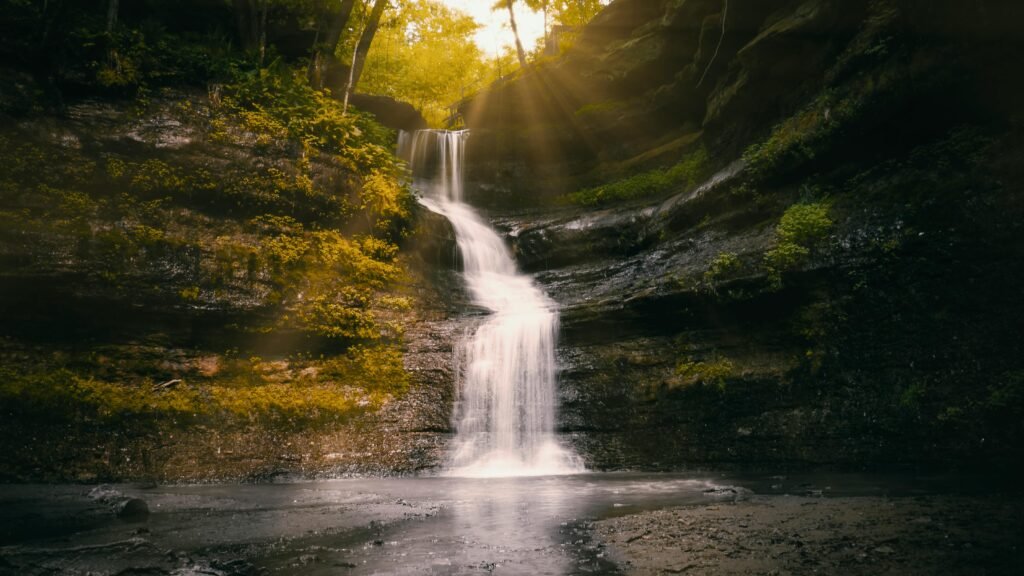 Breathtaking waterfall in Menomonie, WI, illuminated by sunrays and surrounded by lush greenery.